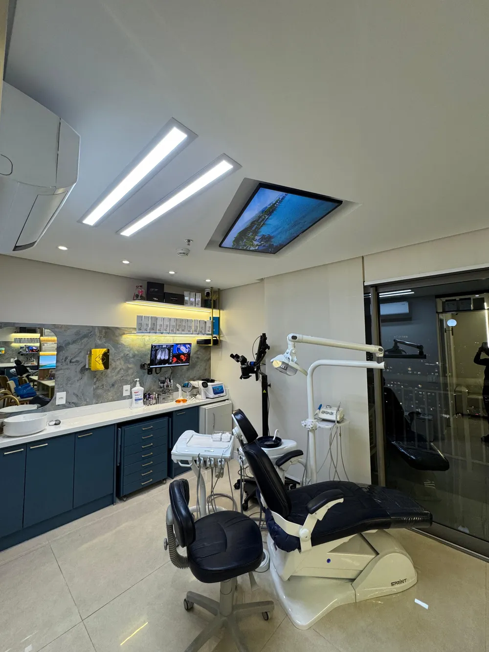 Consultório odontológico de alto padrão da Clínica Mariela Baltazar no Edifício Platina 220, Tatuapé — com microscópio cirúrgico e vista para São Paulo